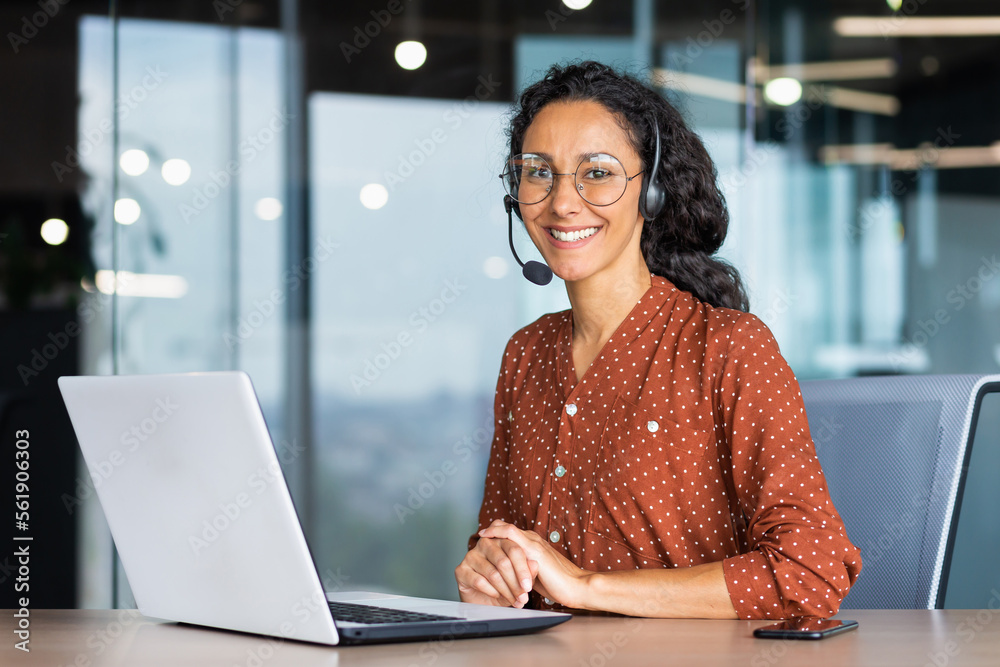 Portrait of Latin American business woman, office worker looking at camera and smiling, using headset and laptop for remote online communication, customer support tech call center worker. - obrazy, fototapety, plakaty 