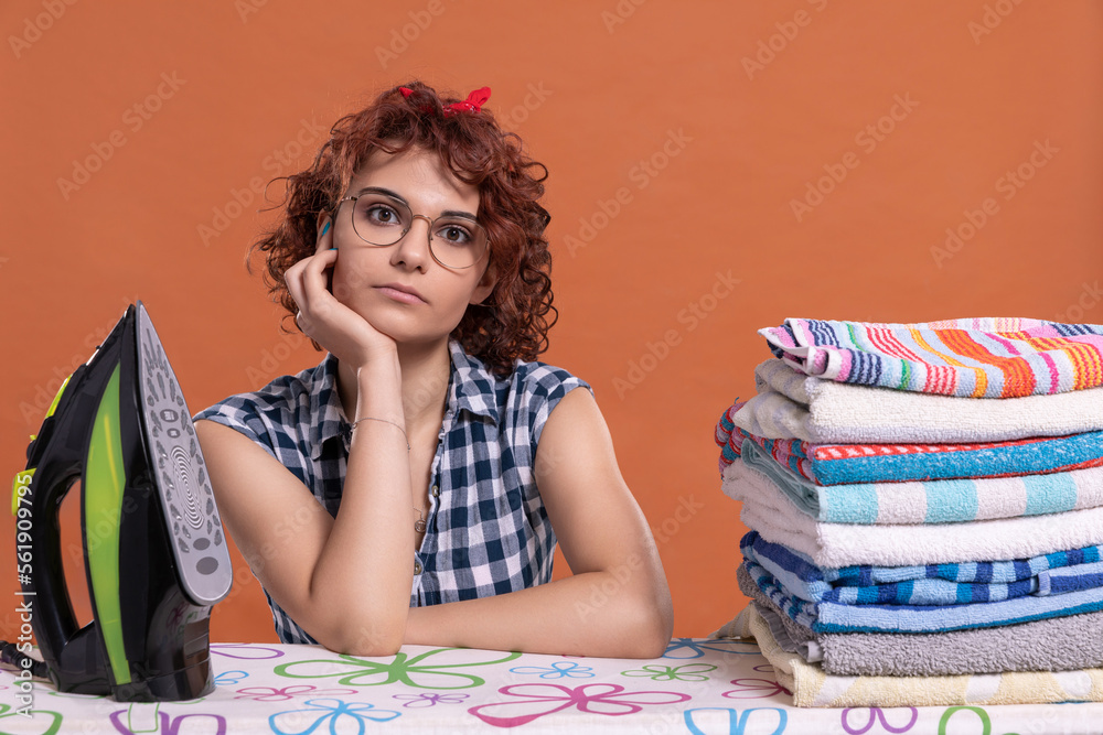 After ironing the towels, the young girl sits and looks straight into the camera. After ironing the towels, the young girl sits and looks straight into the camera.