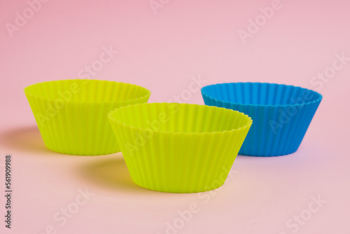 Blue and yellow silicone cupcake molds on a pink paper background