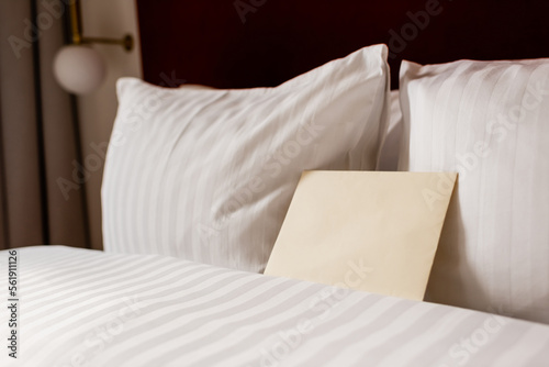 yellow envelope on white and clean bedding in hotel room. photo