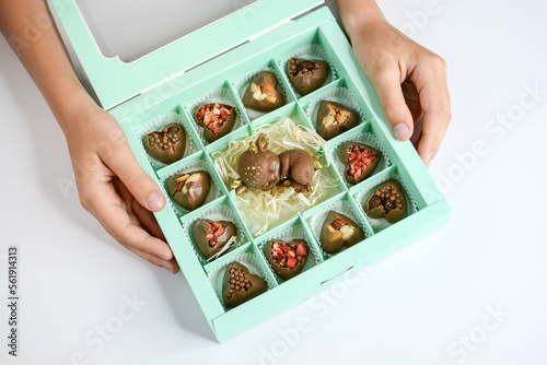 Chocolate cute fawn and candies with various fillings in a gift box. Child's hands hold a box of delicious chocolates