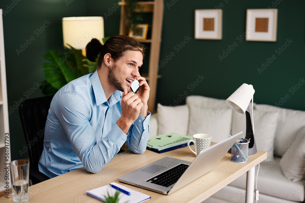 Young happy man talking on the phone in home office Young happy man talking on the phone in home office