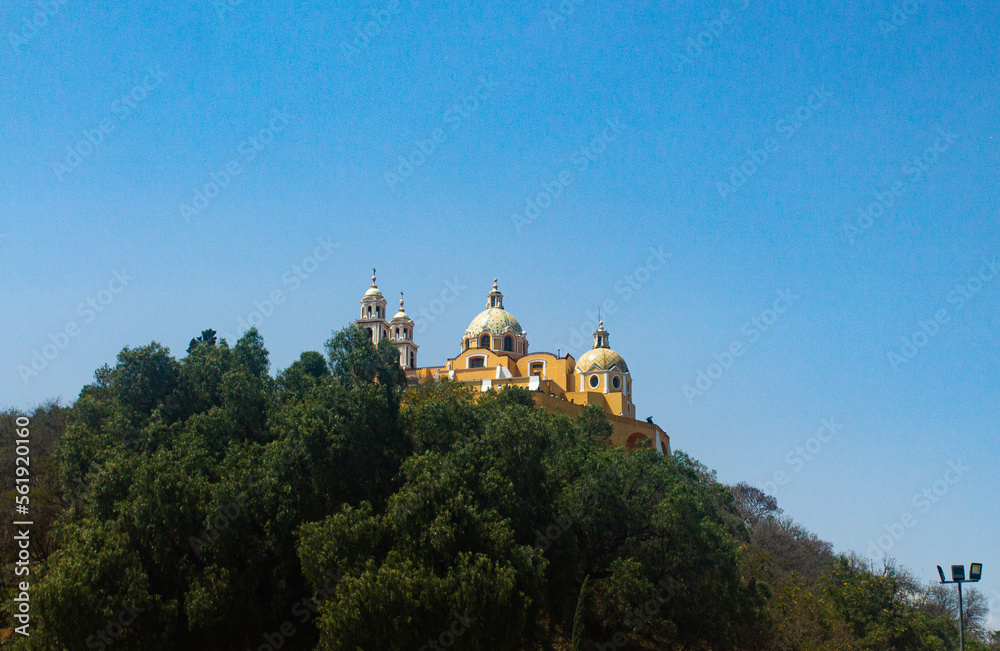 Church of Cholula, Puebla, Mexico. Yellow Church on a mountain with a blue sky in the background.