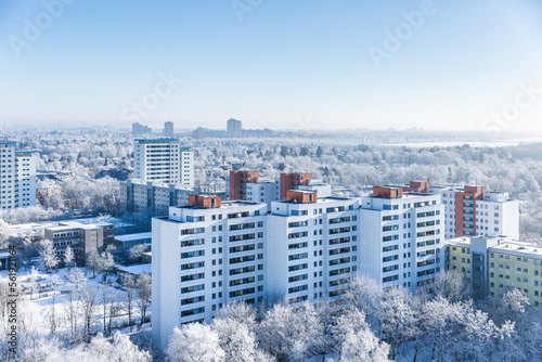 Verschneite Wohnsiedlung mit Winterlandschaft im Hintergrund (ID: 561921164)