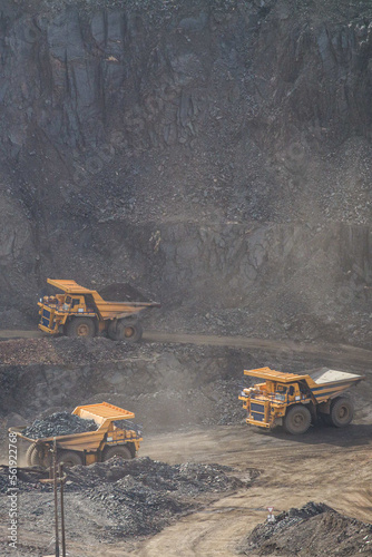 Large yellow dump trucks engaged in the transportation of rock mass in the quarry for mining. Machinery and equipment for iron ore mining