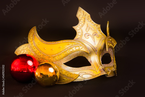 Yellow carnival mask with Christmas toys on a black background.