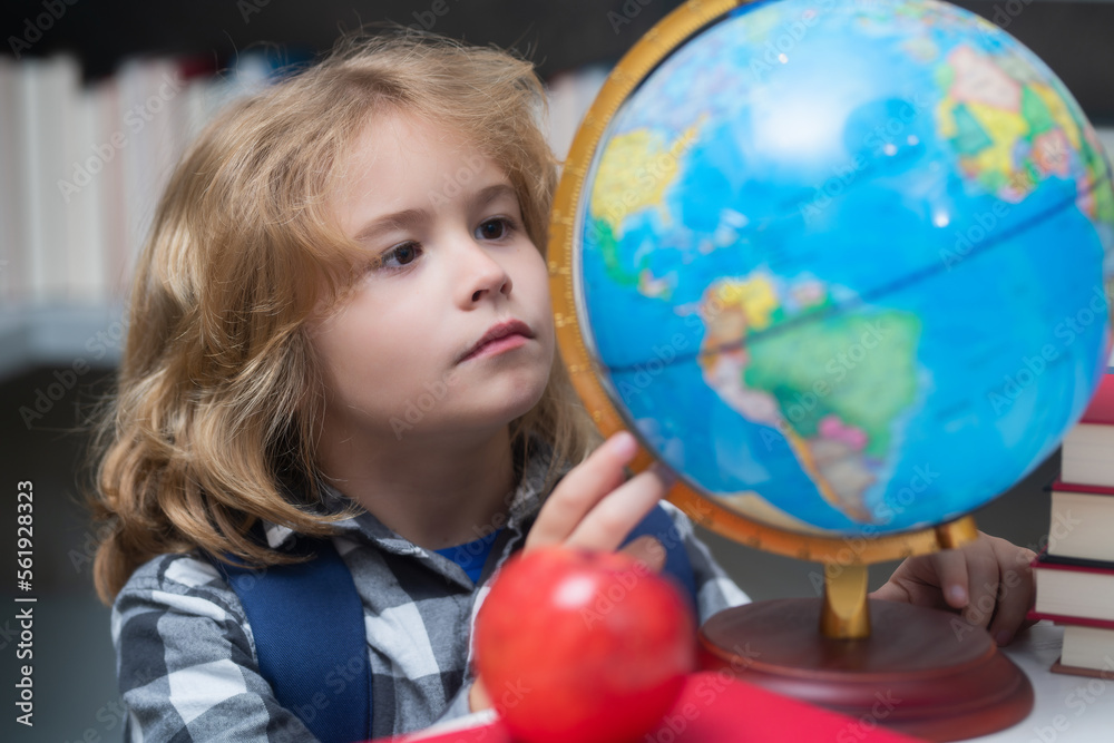 School kid looking at globe in library at the elementary school. Child from elementary school. Pupil go study. Clever schoolboy learning. Kids study, knowledge and education concept. School kid looking at globe in library at the elementary school. Child from elementary school. Pupil go study. Clever schoolboy learning. Kids study, knowledge and education concept.