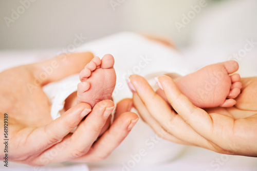 Parents holding tiny feet of newborn baby