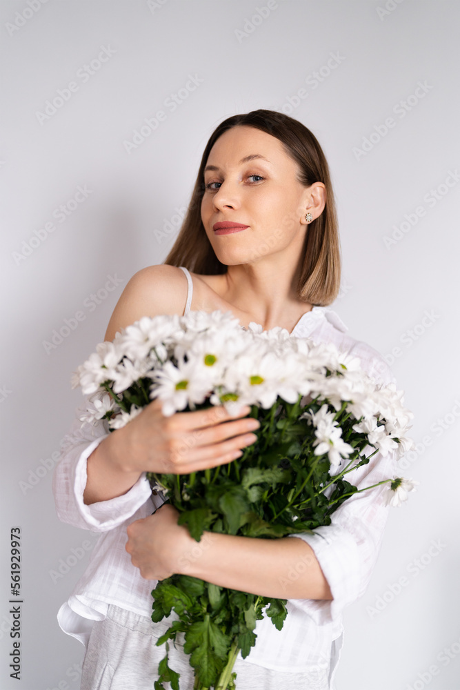 Young beautiful cute sweet lovely smiling woman with hold a bouquet of white fresh flowers on white wall background Young beautiful cute sweet lovely smiling woman with hold a bouquet of white fresh flowers on white wall background
