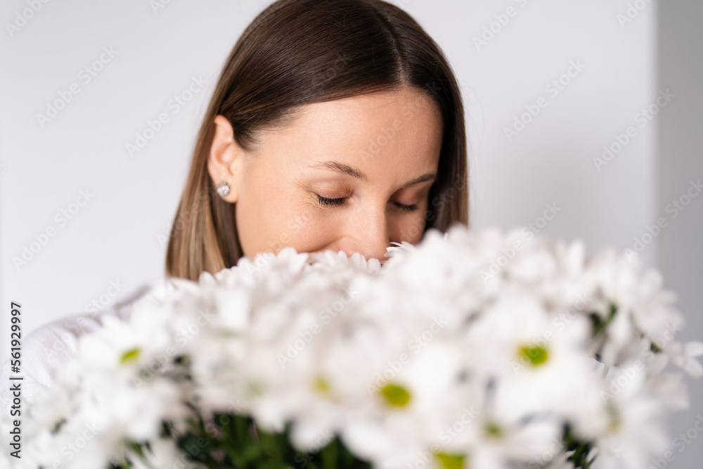 Good looking Caucasian woman smells flowers, she is happy for get a fresh bouquet of white chrysanthemum Good looking Caucasian woman smells flowers, she is happy for get a fresh bouquet of white chrysanthemum
