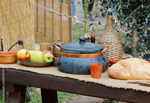 Food, pots and bottles on a wooden table at the Pumpkin Festival medieval historical reenactment in Terzo d'Aquileia, Italy photo