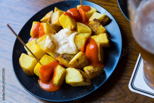 Top view of Patatas bravas, traditional Spanish dish of fried potatoes served with cheese sauce and spicy sauce with paprika. High quality photo