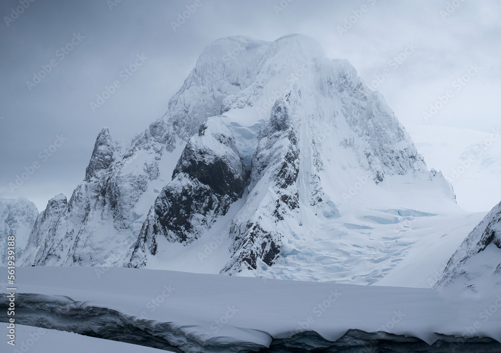 Mountain snowy peaks of Petermann Island in Antarctica, wit overcast grey sky. 