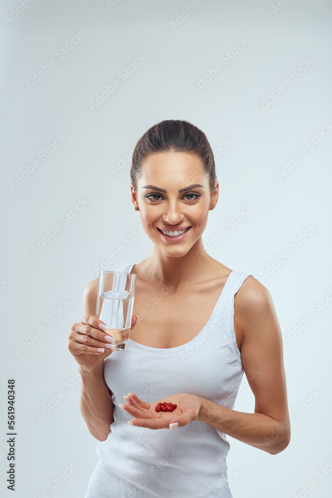 Portrait Of Beautiful Smiling Young Woman With Vitamin Pills. Happy Girl Holding Medications And Glass Of Fresh Water In Hand. Portrait Of Beautiful Smiling Young Woman With Vitamin Pills. Happy Girl Holding Medications And Glass Of Fresh Water In Hand.