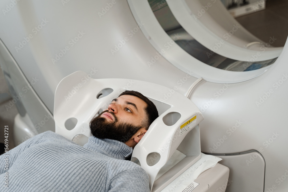 CT scan of brains of man in medical clinic. Man is doing computed tomography x-ray examination of tumor in his head in a CT scan room. CT scan of brains of man in medical clinic. Man is doing computed tomography x-ray examination of tumor in his head in a CT scan room.