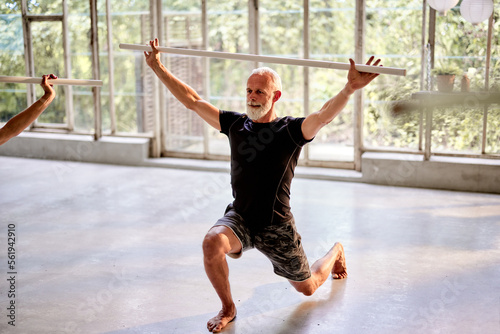 Mature man doing stick yoga photo
