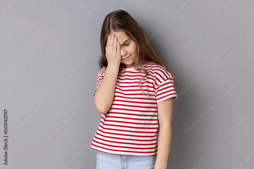 Oh no, I forgot. Portrait of little girl wearing striped T-shirt making facepalm gesture, feeling regret and shame about forgotten event, bad memory. Indoor studio shot isolated on gray background. Oh no, I forgot. Portrait of little girl wearing striped T-shirt making facepalm gesture, feeling regret and shame about forgotten event, bad memory. Indoor studio shot isolated on gray background.
