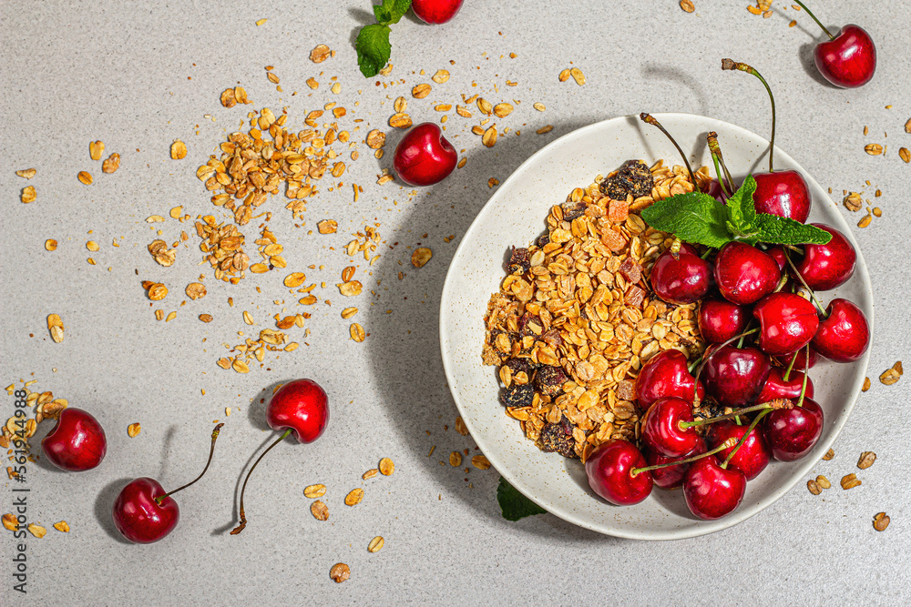 Summer breakfast concept. Healthy morning food. Ripe cherries and granola, light concrete background Summer breakfast concept. Healthy morning food. Ripe cherries and granola, light concrete background