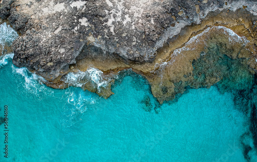 Fotografia aérea da linha da costa rochosa que entra pela água azul turquesa