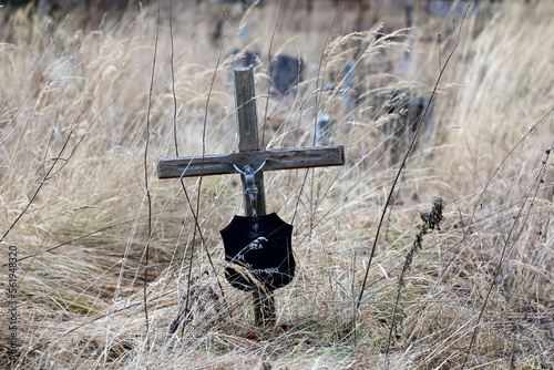 Stary  zardzewiały stalowy krzyż na cmentarzu wojennym. Krzaki. 