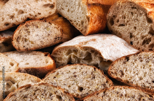 Closeup of a variety of fresh baked loaves of bread, the loaves are cut in half and sliced.