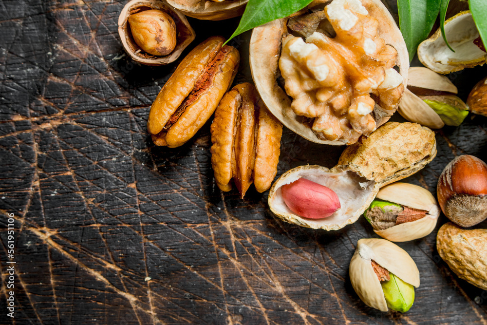 Nuts background. Assortment of different nuts with green leaves . Nuts background. Assortment of different nuts with green leaves .