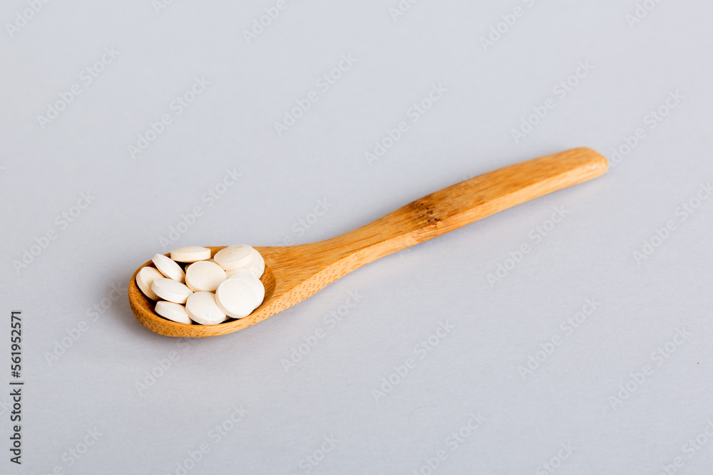 Heap of white pills on colored background. Tablets scattered on a table. Pile of red soft gelatin capsule. Vitamins and dietary supplements concept Heap of white pills on colored background. Tablets scattered on a table. Pile of red soft gelatin capsule. Vitamins and dietary supplements concept