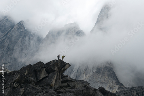 Two hikers on rocky spire in misty mountains, Bugaboo Provincial Park, Radium, British Columbia, Canada. photo