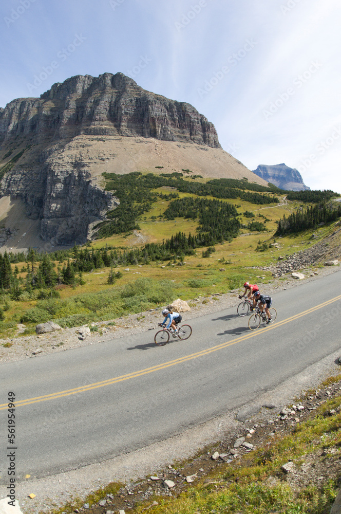 Cyclists climb a hill with a mountain in the distance. Cyclists climb a hill with a mountain in the distance.