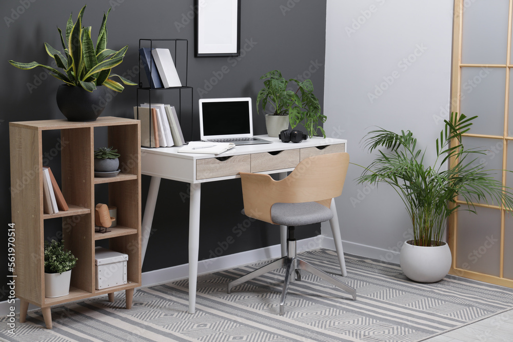 Workplace with laptop, stationery on desk and chair in home office Workplace with laptop, stationery on desk and chair in home office