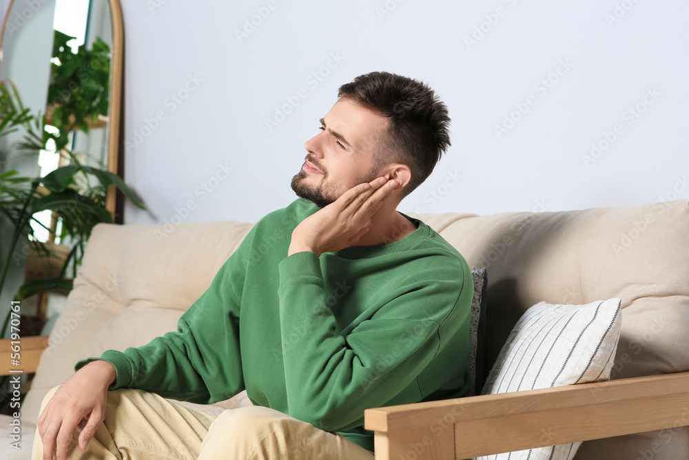 Obraz premium Young man suffering from ear pain at home