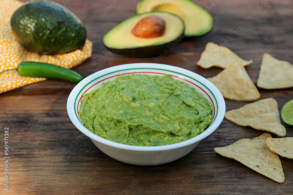 Delicious guacamole made of avocados with nachos on wooden table Delicious guacamole made of avocados with nachos on wooden table
