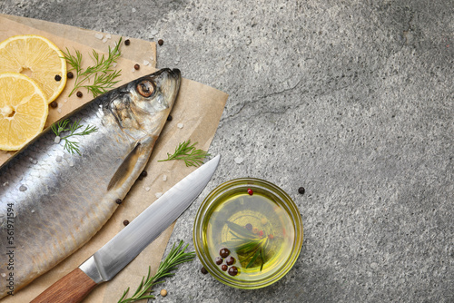 Delicious salted herring, olive oil, lemon and rosemary on grey table, flat lay. Space for text