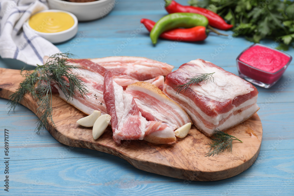 Pieces of pork fatback with garlic and dill on light blue wooden table Pieces of pork fatback with garlic and dill on light blue wooden table