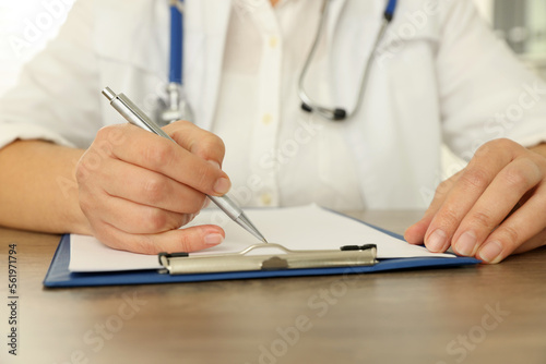Doctor writing at wooden table  closeup view