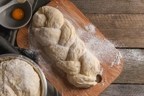Homemade braided bread and ingredients on wooden table, flat lay. Cooking traditional Shabbat challah