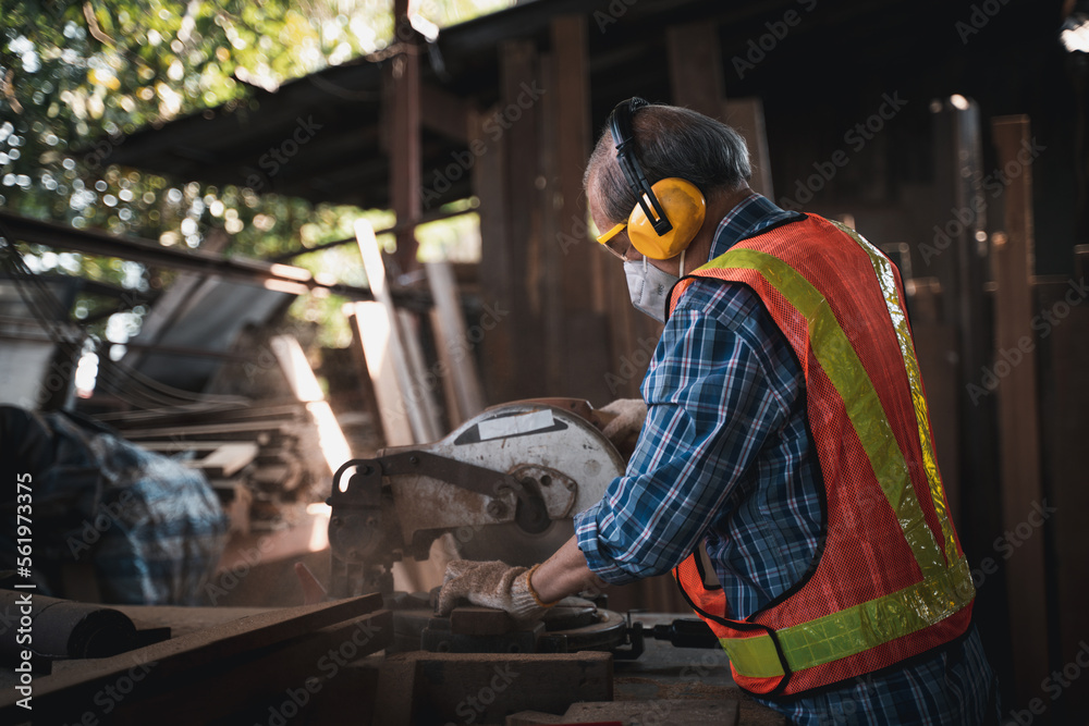 An elderly carpenter works the wood with meticulous care. An elderly carpenter works the wood with meticulous care.