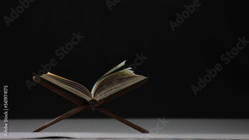 Slow motion of The Quran, the Muslim holy book, lies on a black background wooden board