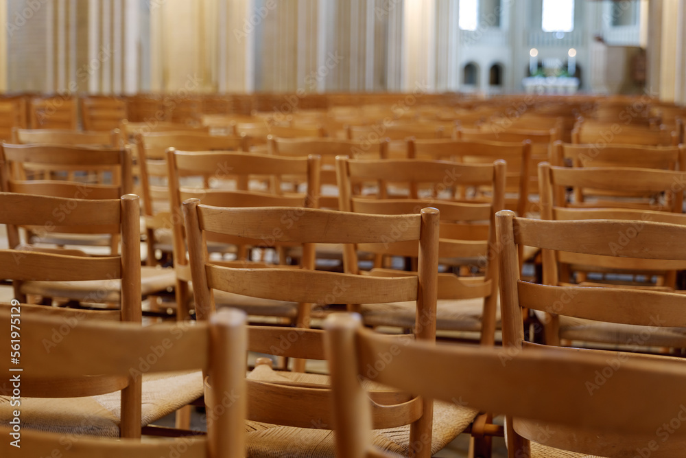 Selective focus view at row of chairs without people for worshipper at nave of Protestant Church. 