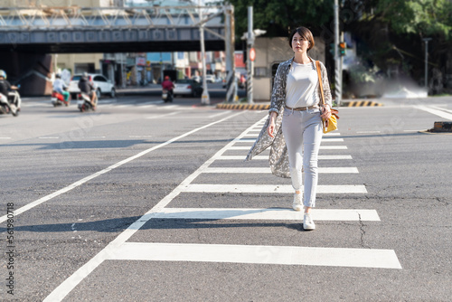 Stylish young Asian girl walking. Active walking across the zebra crosswalk Taipei.