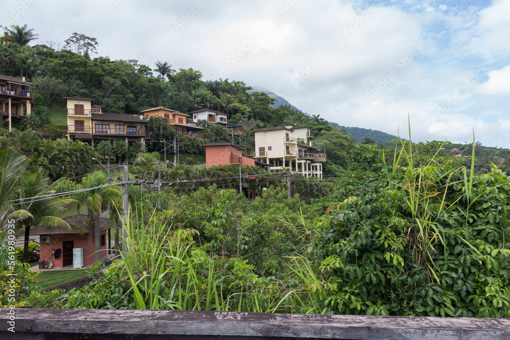 Casas no morro do Veloso - ILHABELA, SP, BRAZIL - NOVEMBER 30, 2022: Houses built on the hill overlooking Veloso beach, in the middle of the lush Atlantic Forest.