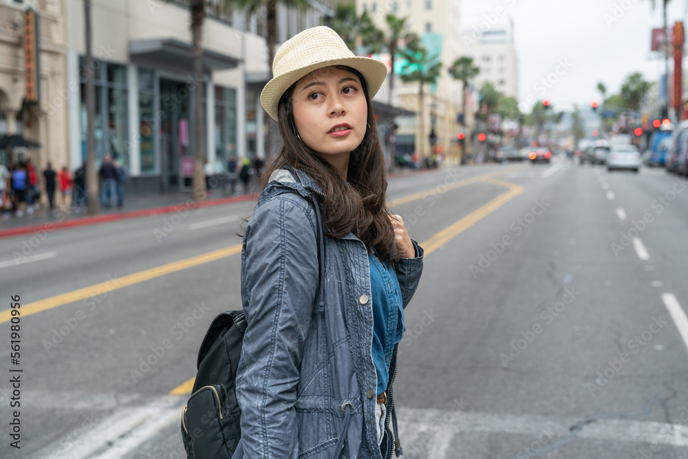 young asian girl crosses the road at the zebra crossing while enjoying spring vacation.