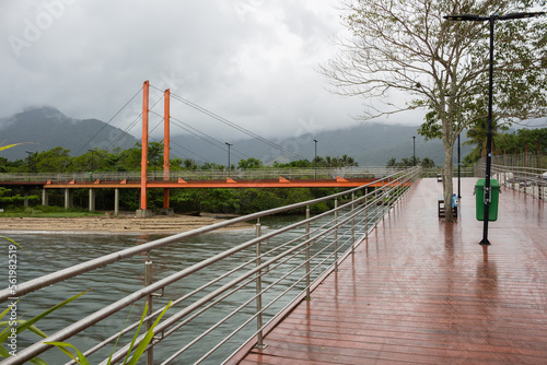 Ponte Estaiada - ILHABELA, SP, BRAZIL - NOVEMBER 28, 2022: Cable-stayed bridge on Barra Velha beach on a cloudy day, which is used by pedestrians and cyclists, built with a plastic wood floor.