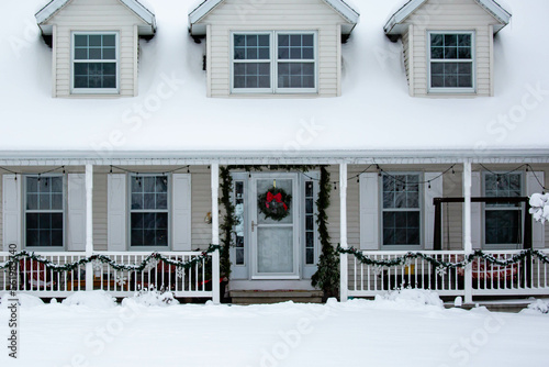 Front door of house decorated with Christmas decorations and snow © mtatman