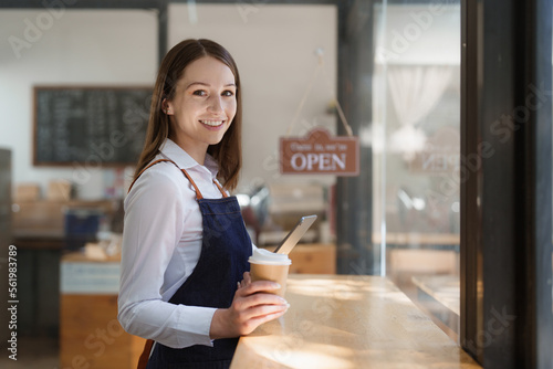 Young Female manager in restaurant with tablet. Woman coffee shop owner with open sign. Small business concept