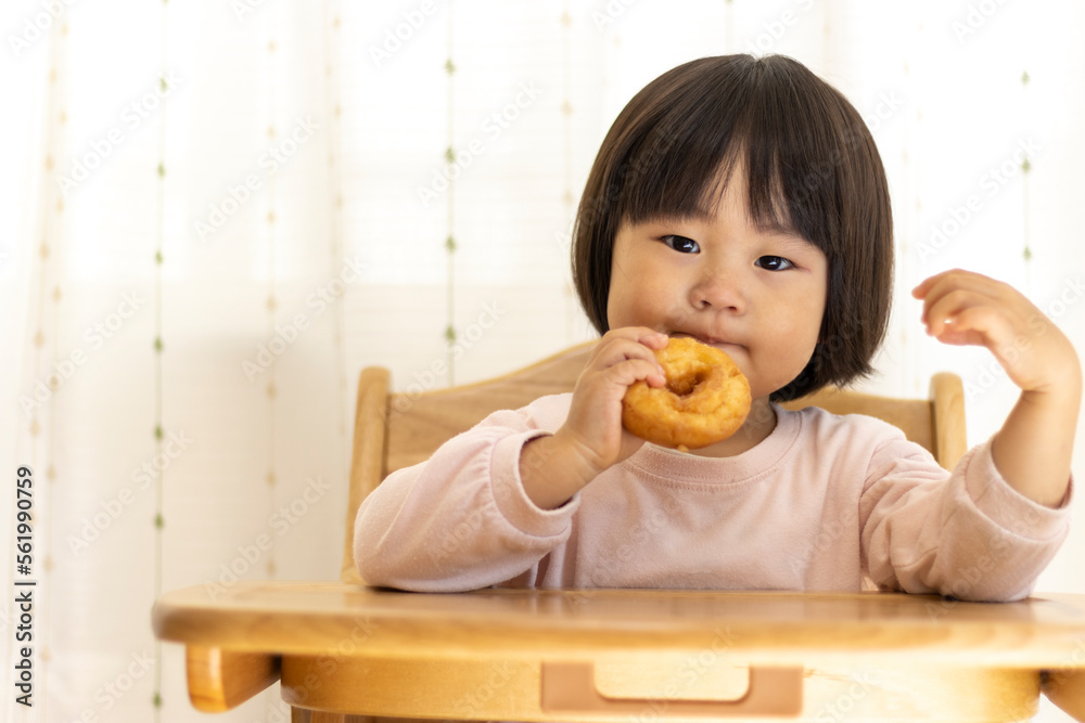 座ってドーナッツを食べる赤ちゃん(2歳4か月、女の子、日本人)