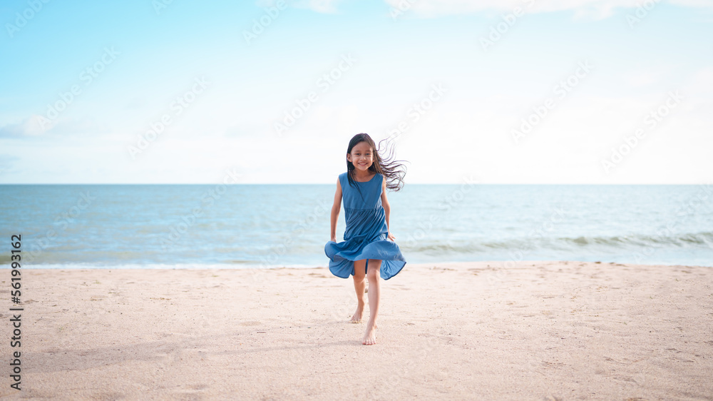 Happy and healthy asian little girl is running on the beach with happy moment for holiday vacation time. Concept of travel, nature, outdoor activity for kid.