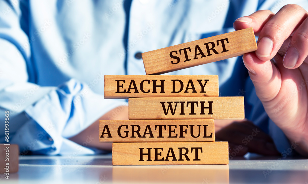 Closeup on businessman holding a wooden block with "Start Each Day With a Grateful Heart" message - obrazy, fototapety, plakaty 