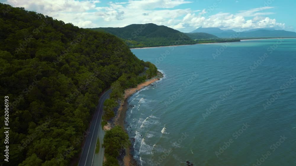 Aerial drone bird view of modern silver car driving on road along the seaside coast with sandy beach and lush green tree forest and blue sea waves in 4K. Follow along a street in nature traveling cars Aerial drone bird view of modern silver car driving on road along the seaside coast with sandy beach and lush green tree forest and blue sea waves in 4K. Follow along a street in nature traveling cars