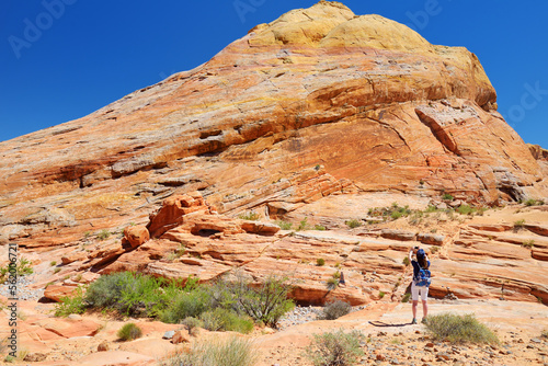 Young female hiker exploring amazing sandstone formations in Valley of Fire State Park, Nevada, USA.